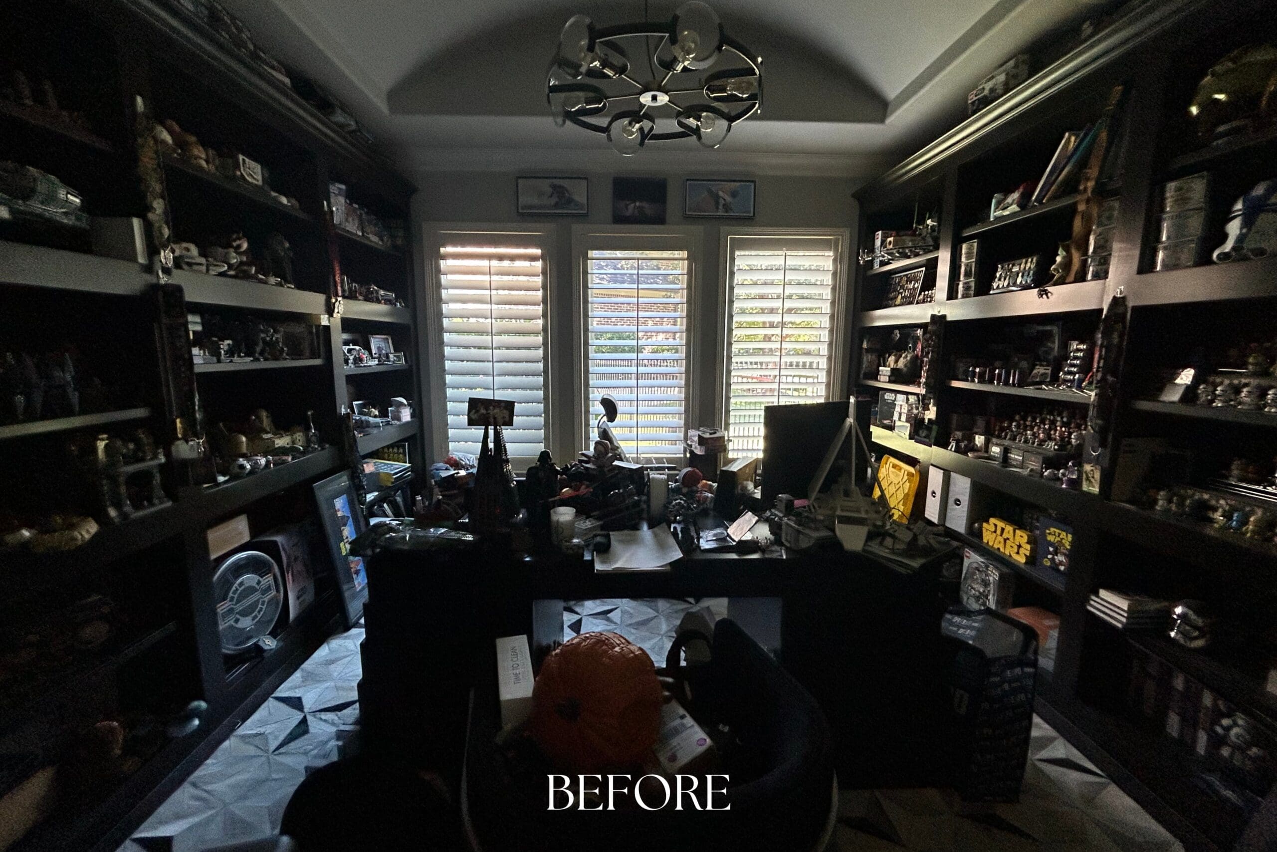 Cluttered home office before renovation with dark built-in shelves full of collectibles