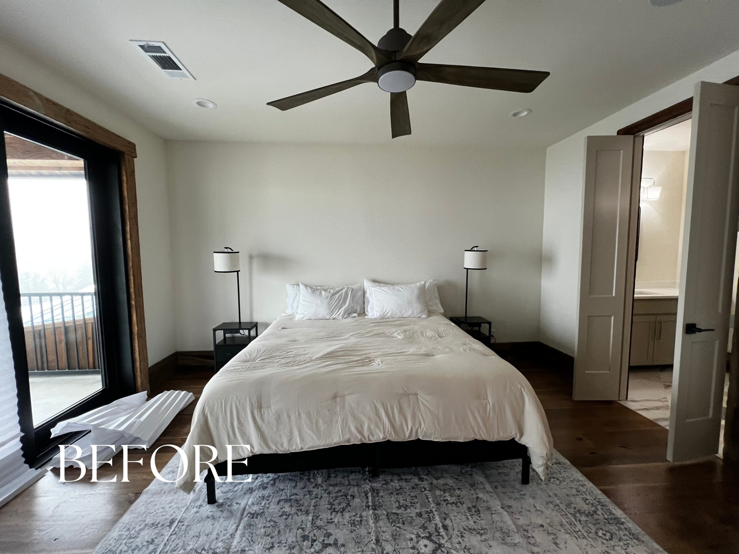 Before photo of a plain guest bedroom featuring white walls, a basic bed, and a ceiling fan before a professional turnkey design transformation.