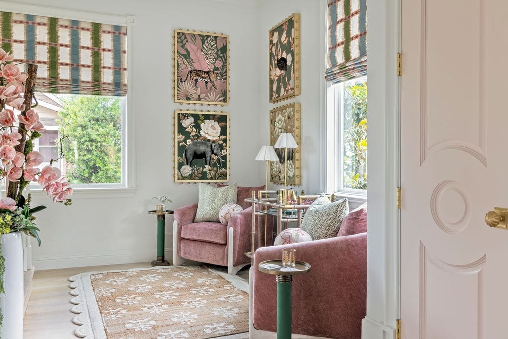 A bold, colorful stair parlor turned ladies' lounge for cocktail hour, featuring pink armchairs, a sisal rug layered over wool, and a gallery of animal art designed by Baker Design Group.